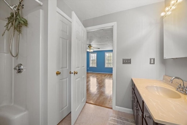 bathroom featuring tile patterned floors, walk in shower, ceiling fan, and vanity