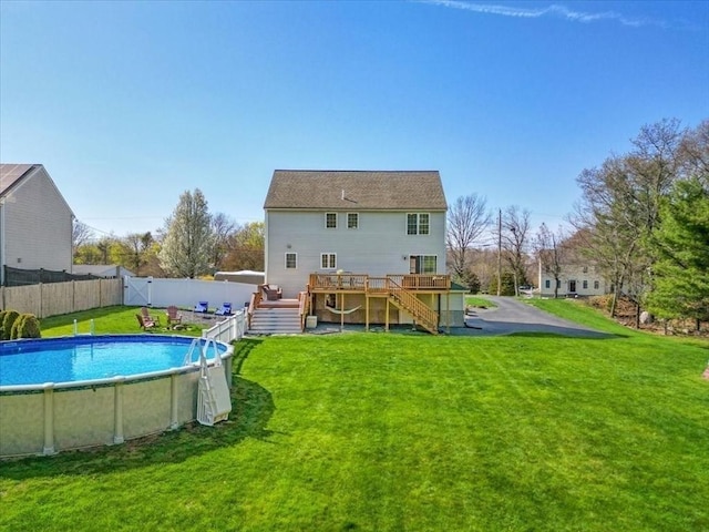 back of house with a fenced backyard, a wooden deck, a lawn, and stairway