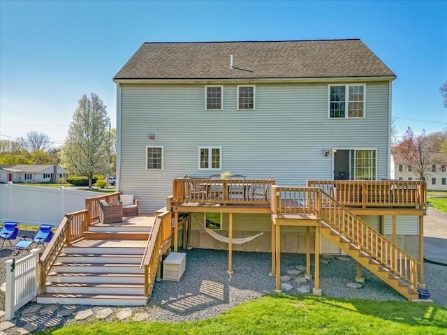 rear view of house with fence, roof with shingles, a wooden deck, and stairway