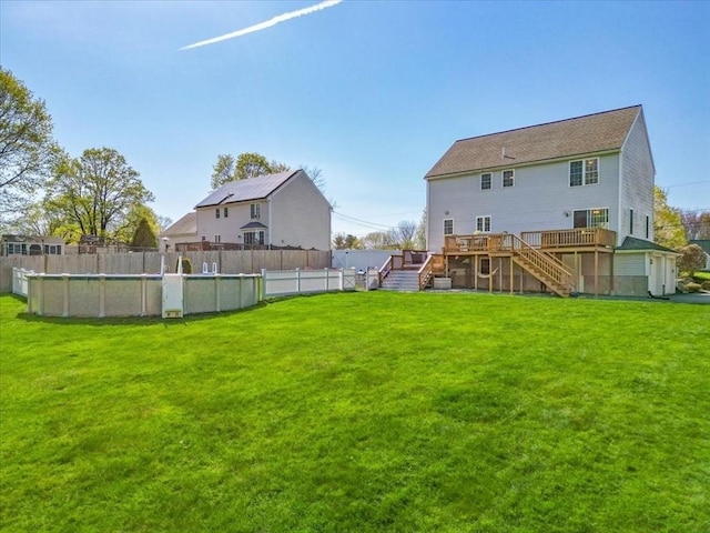back of property featuring fence, a wooden deck, a lawn, and stairway