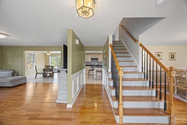 stairway with a ceiling fan and wood finished floors