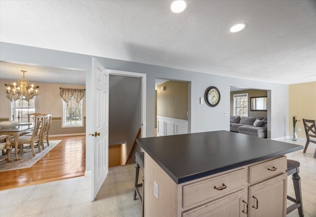 kitchen with an inviting chandelier, baseboards, dark countertops, and a kitchen bar