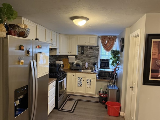 808 Walnut St, Fall River, MA 02720 - kitchen featuring under cabinet range hood, dark wood-style flooring, backsplash, dark countertops, and appliances with stainless steel finishes