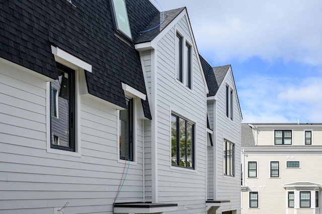 view of side of home with roof with shingles