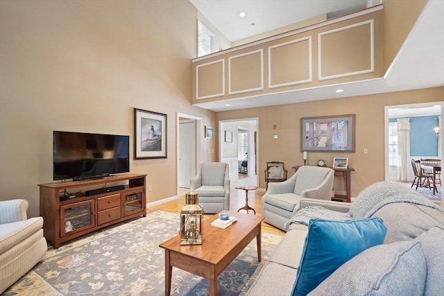 living area featuring wood finished floors, recessed lighting, a high ceiling, an inviting chandelier, and baseboards