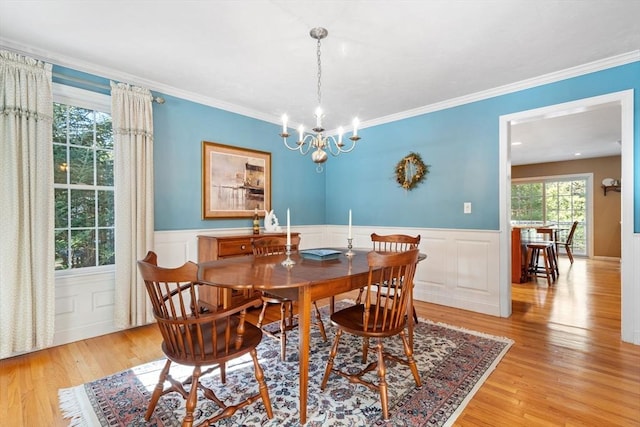 dining area featuring light wood-style floors, wainscoting, and crown molding