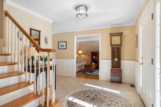 foyer entrance with light tile patterned floors, a wainscoted wall, stairs, and visible vents