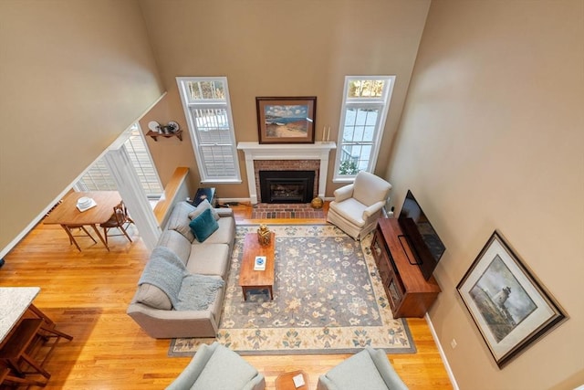 living room featuring baseboards, a high ceiling, wood finished floors, and a fireplace