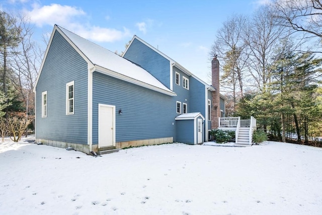 snow covered back of property featuring a wooden deck