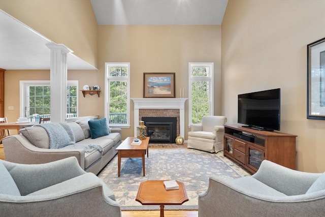 living room with lofted ceiling, a brick fireplace, and decorative columns