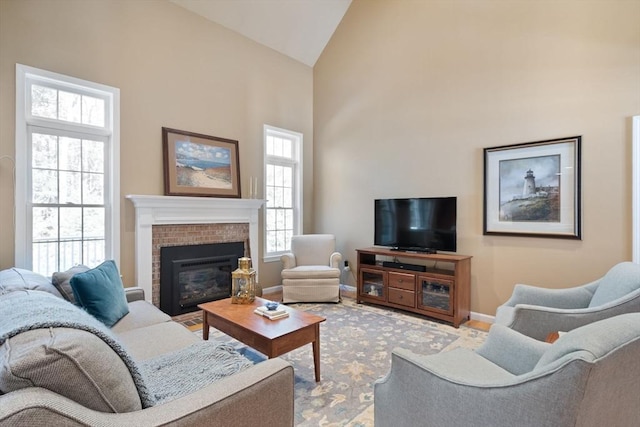 living area featuring a fireplace, high vaulted ceiling, and baseboards