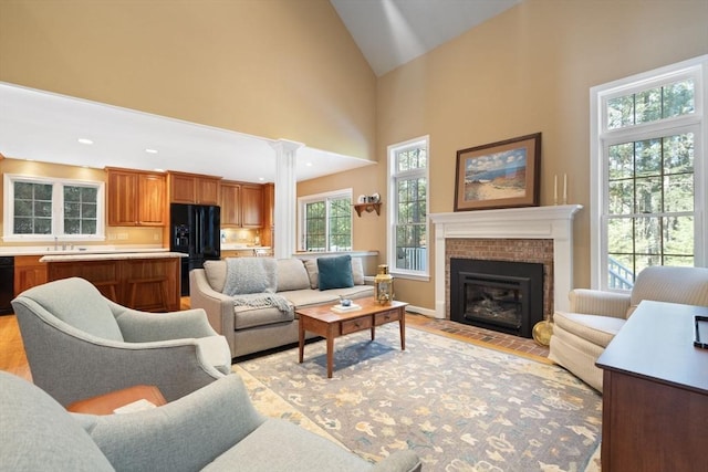 living area with recessed lighting, decorative columns, a fireplace with flush hearth, and high vaulted ceiling