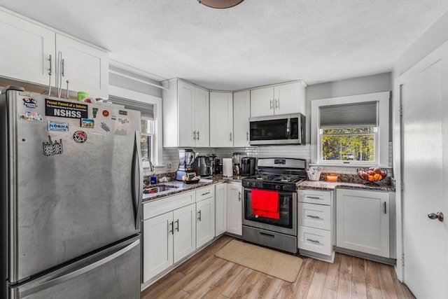 kitchen featuring white cabinetry, stainless steel appliances, tasteful backsplash, and a sink
