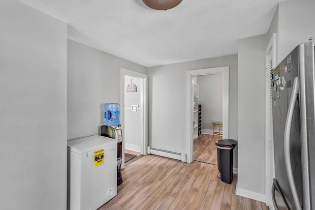 hallway with baseboards, baseboard heating, and light wood-style floors