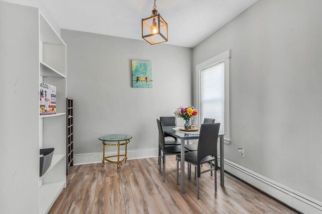 dining space with baseboards, wood finished floors, and baseboard heating