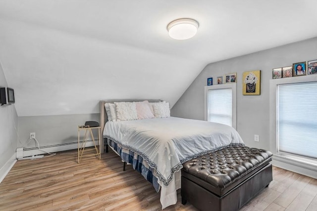 bedroom with lofted ceiling, baseboards, baseboard heating, and wood finished floors