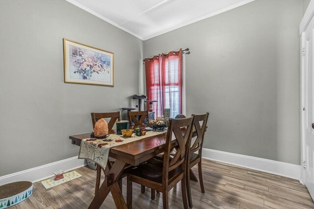 dining room with wood finished floors, baseboards, and ornamental molding
