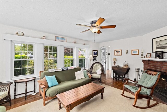 590 Hatherly Rd, Scituate, MA 02066 - living room with wood finished floors, healthy amount of natural light, a textured ceiling, ceiling fan, and a brick fireplace