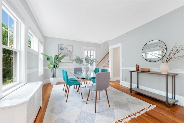 dining room with stairway, light wood-type flooring, ornamental molding, and baseboards