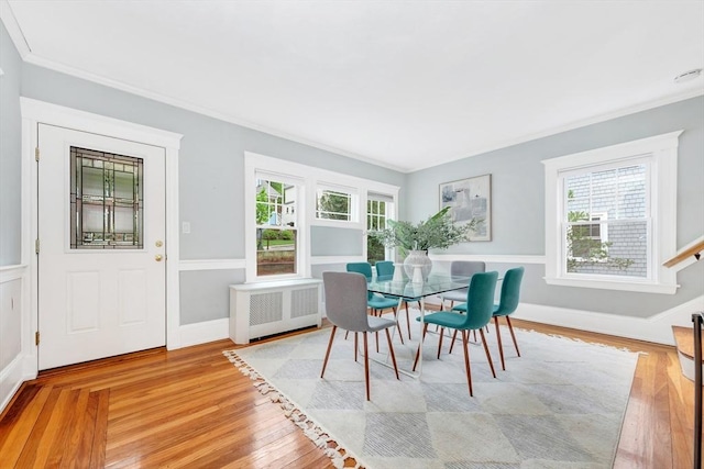 dining space with radiator, ornamental molding, wood finished floors, and baseboards