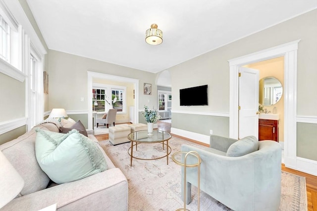 living room with light wood-style flooring, baseboards, and arched walkways