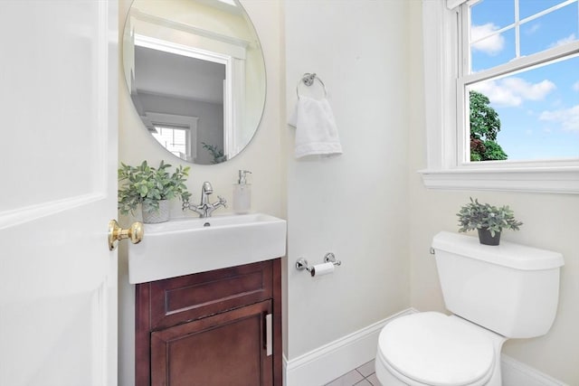 half bathroom with toilet, plenty of natural light, vanity, and baseboards