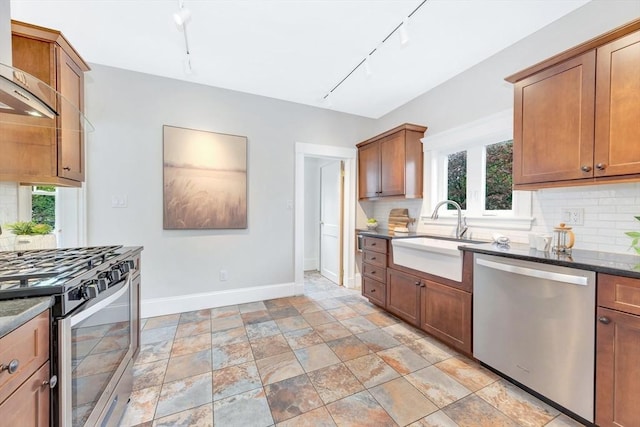 kitchen with appliances with stainless steel finishes, baseboards, a sink, and backsplash