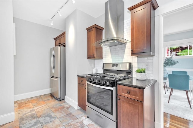 kitchen with appliances with stainless steel finishes, wall chimney exhaust hood, baseboards, decorative backsplash, and rail lighting