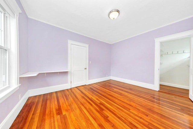 spare room featuring baseboards, wood finished floors, and ornamental molding