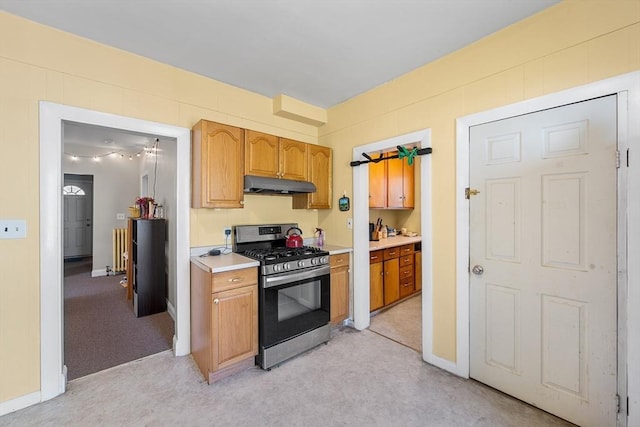 115 Elm St, Somerville, MA 02144 - kitchen featuring stainless steel range with gas stovetop, under cabinet range hood, light countertops, light carpet, and brown cabinets