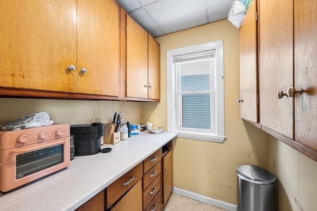 115 Elm St, Somerville, MA 02144 - kitchen with brown cabinetry, light countertops, baseboards, and a paneled ceiling