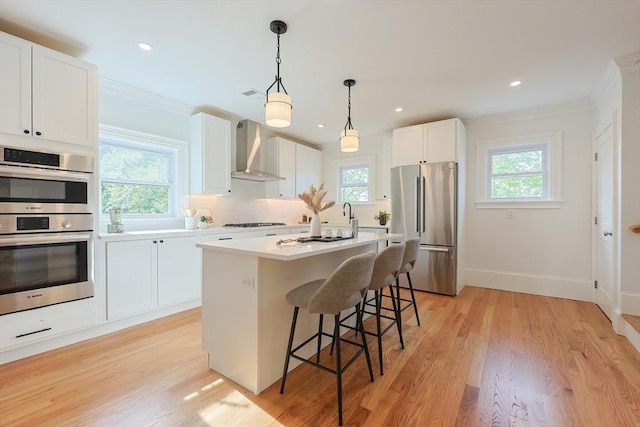 179 Main Unit 2, Medford, MA 02155 - kitchen featuring stainless steel appliances, wall chimney range hood, a kitchen bar, crown molding, and light countertops