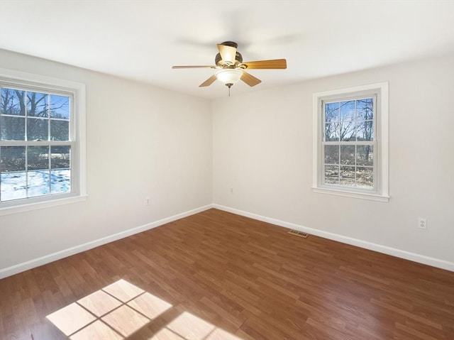 empty room with ceiling fan, baseboards, and wood finished floors