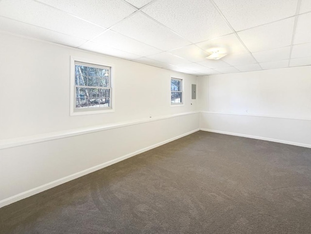 spare room featuring electric panel, a drop ceiling, baseboards, and dark carpet