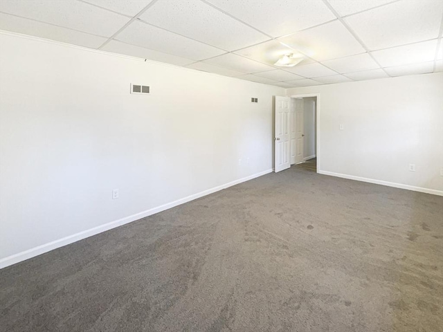 spare room with baseboards, a paneled ceiling, visible vents, and dark carpet