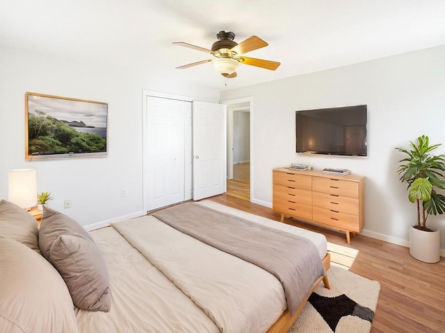 bedroom with light wood finished floors, a closet, baseboards, and a ceiling fan