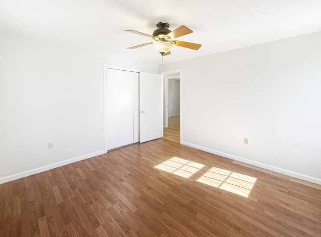 unfurnished bedroom with ceiling fan, a closet, baseboards, and wood finished floors