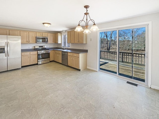 kitchen featuring visible vents, a sink, decorative light fixtures, dark countertops, and appliances with stainless steel finishes