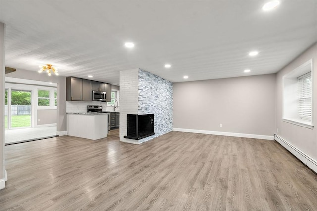 13 Campello Rd, Framingham, MA 01701 - unfurnished living room with baseboard heating, light wood-type flooring, recessed lighting, a multi sided fireplace, and baseboards