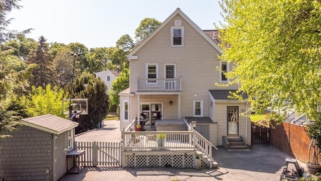 back of property featuring a gate, fence, entry steps, and a balcony