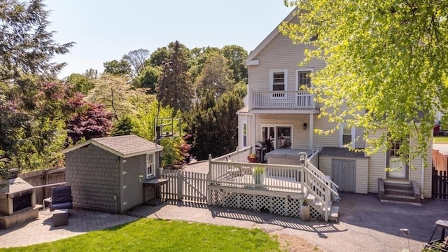 rear view of property featuring a storage shed, fence, an outbuilding, and a wooden deck