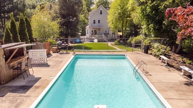 view of swimming pool featuring a patio area and view of scattered trees