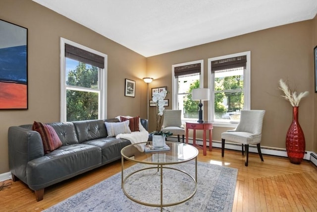 living area with healthy amount of natural light, baseboard heating, baseboards, and light wood finished floors
