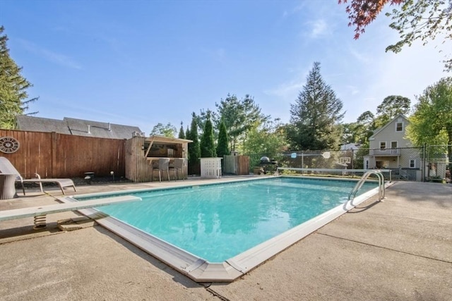 view of pool featuring a fenced backyard, a patio, and a diving board