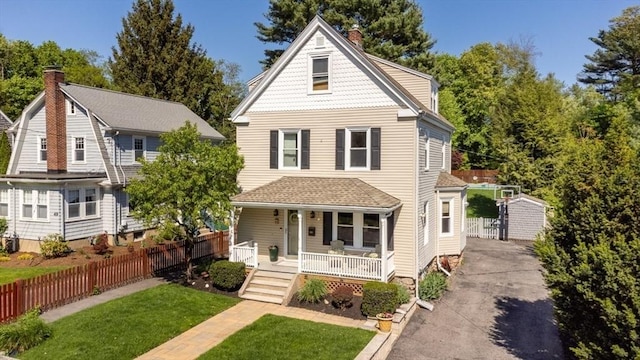 victorian-style house with a porch, a chimney, and asphalt driveway