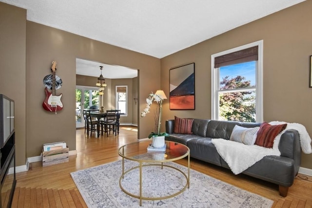 living area featuring a chandelier, light wood-style flooring, and baseboards