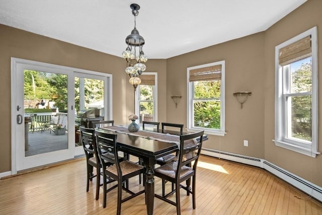 dining area featuring healthy amount of natural light, light wood-style floors, a baseboard heating unit, and baseboards