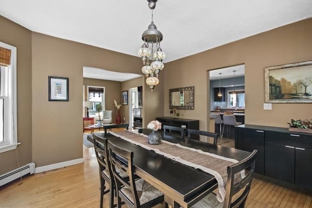 dining room with baseboard heating, light wood finished floors, and plenty of natural light