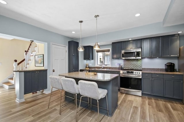kitchen featuring stainless steel appliances, a breakfast bar area, light wood-style flooring, a kitchen island, and recessed lighting