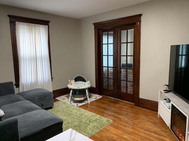 living area featuring french doors, light wood-style floors, plenty of natural light, and baseboards